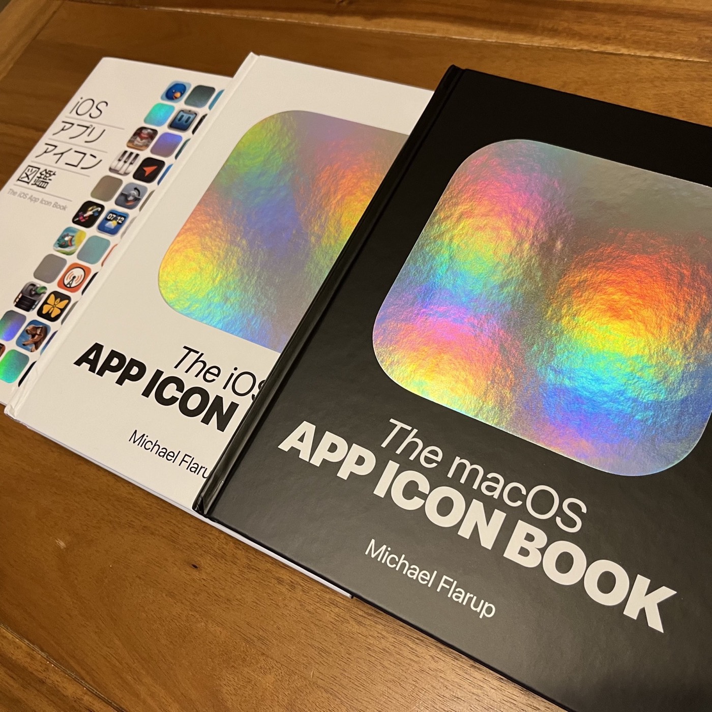 The iOS and macOS App Icon Books catching rainbow light on a wooden table