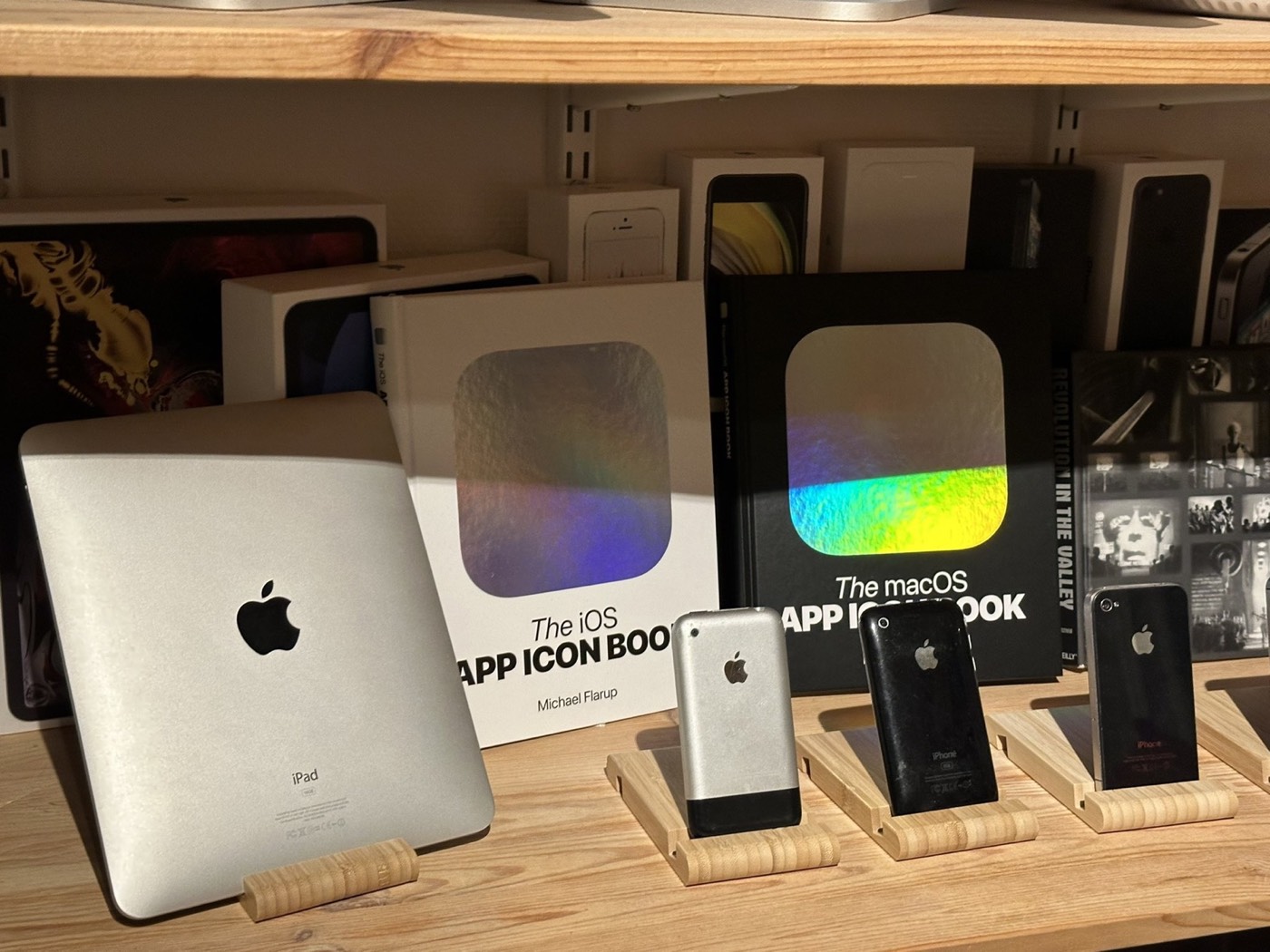 The iOS and macOS App Icon Books displayed among vintage Apple hardware